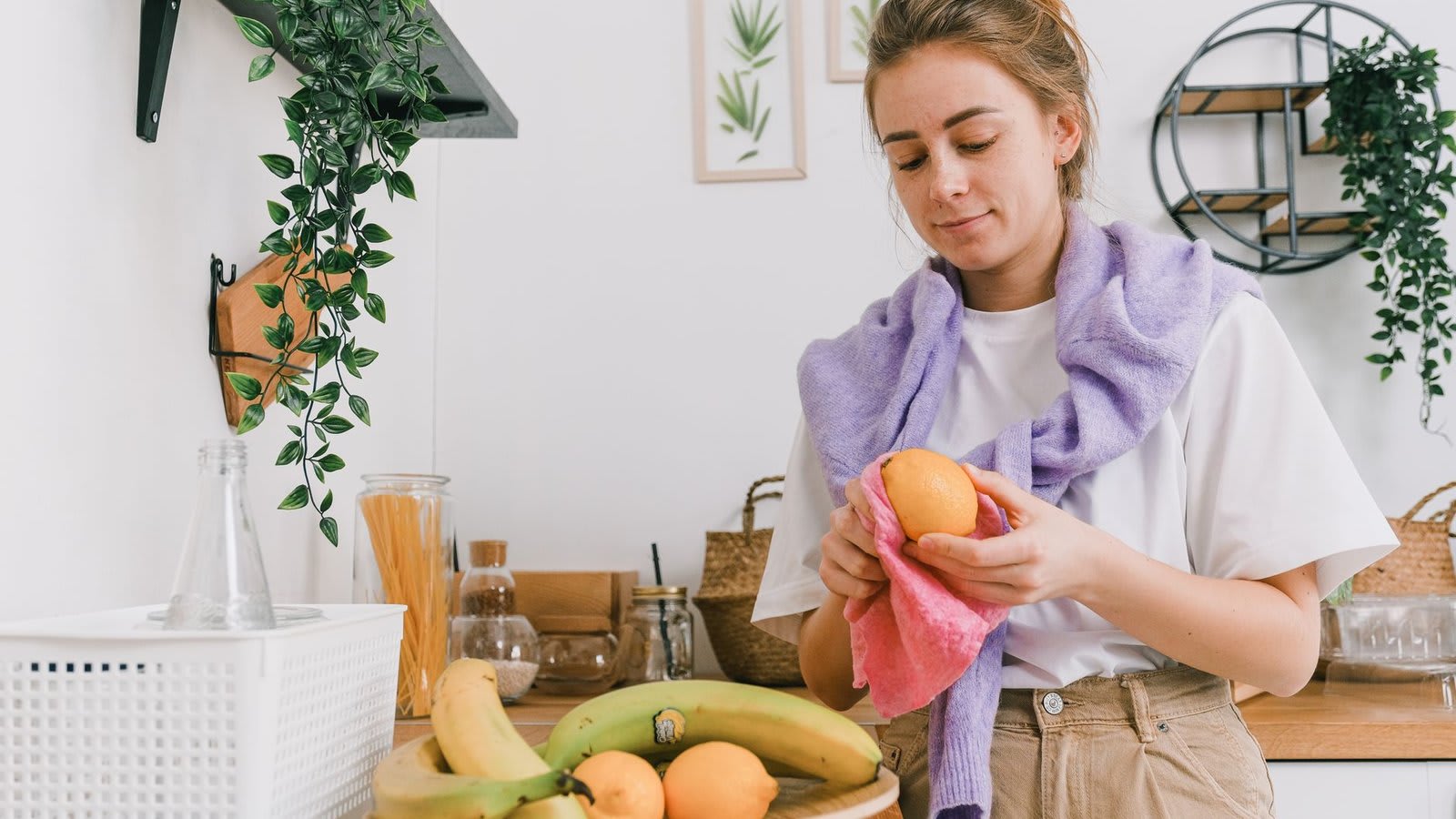 Cozinha organizada com uma fruteira cheia sobre a bancada e potes de vidro com alimentos.