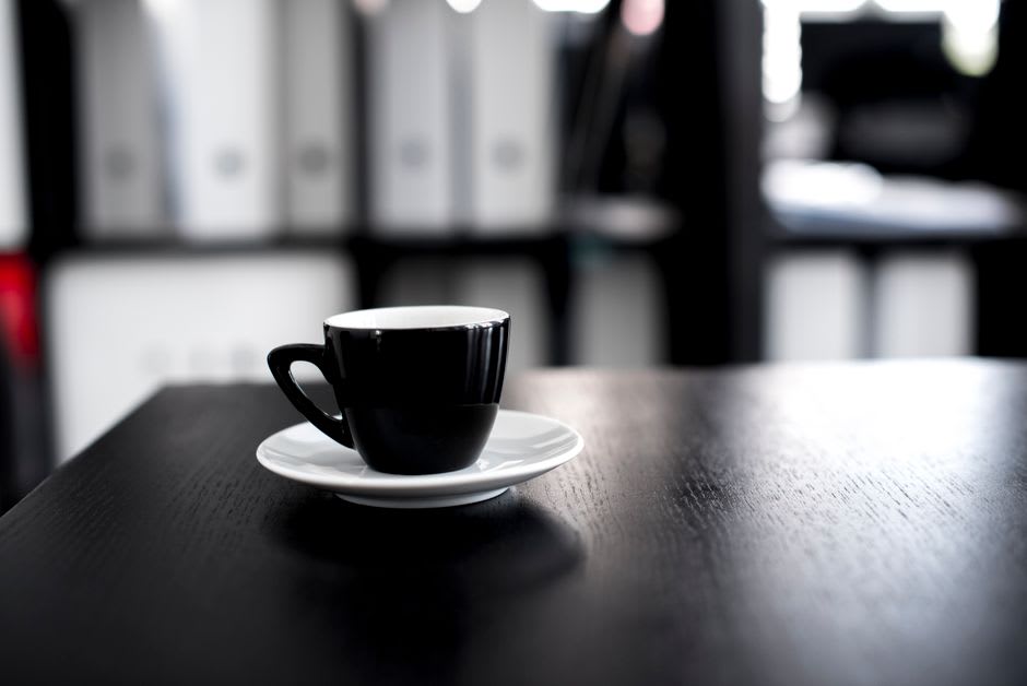 Xícara de café sobre uma mesa de trabalho no meio da tarde