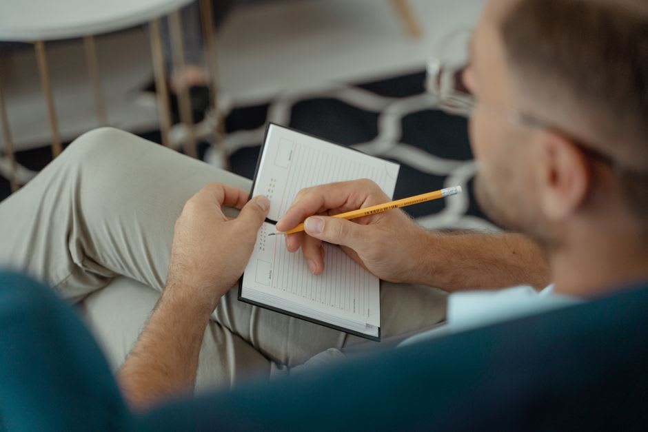 Homem escrevendo em um diário alimentar em um caderno