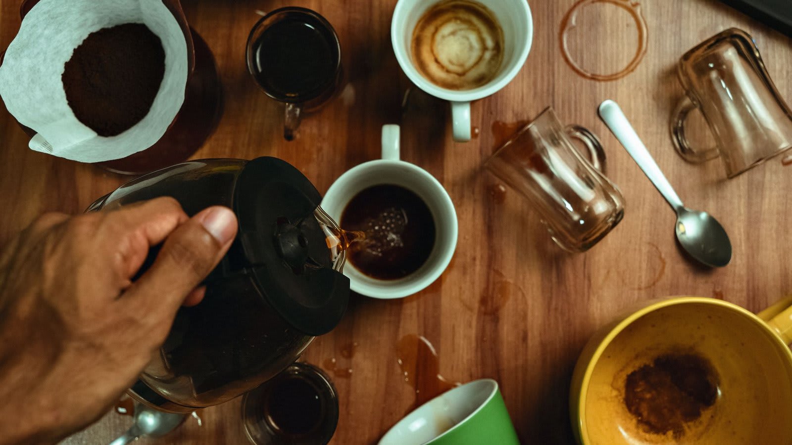 Mãos servindo café pela manhã na cozinha.
