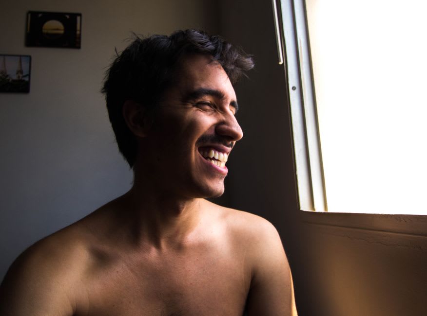 Homem recebendo luz do sol da manhã ao lado de uma janela