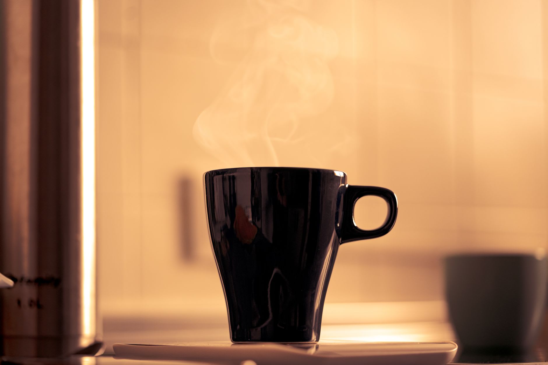 Xícara de café preto fumegante sobre a bancada da cozinha na luz da manhã.