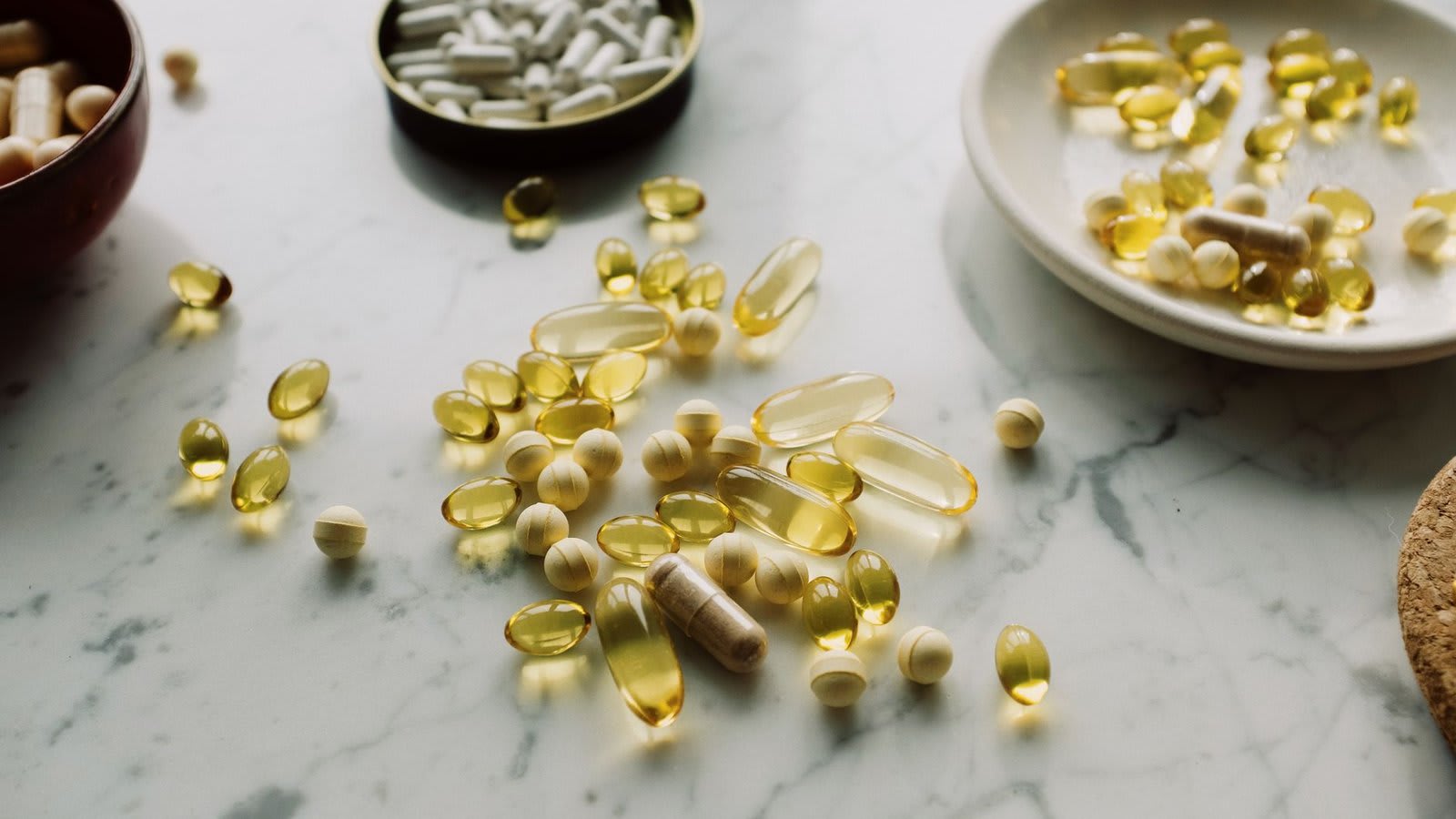 Cápsulas de vitamina D ao lado de uma janela ensolarada.