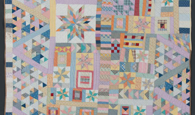 Album quilt photo showing multicolored patchwork with pink accents. 