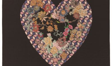 A quilt with a geometric heart-shaped design with floral accents 