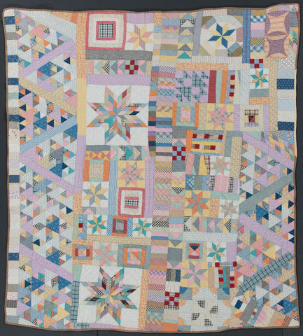 Album quilt photo showing multicolored patchwork with pink accents. 