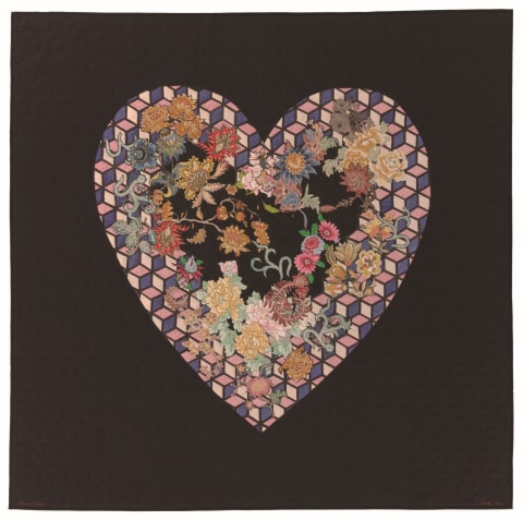 A quilt with a geometric heart-shaped design with floral accents 