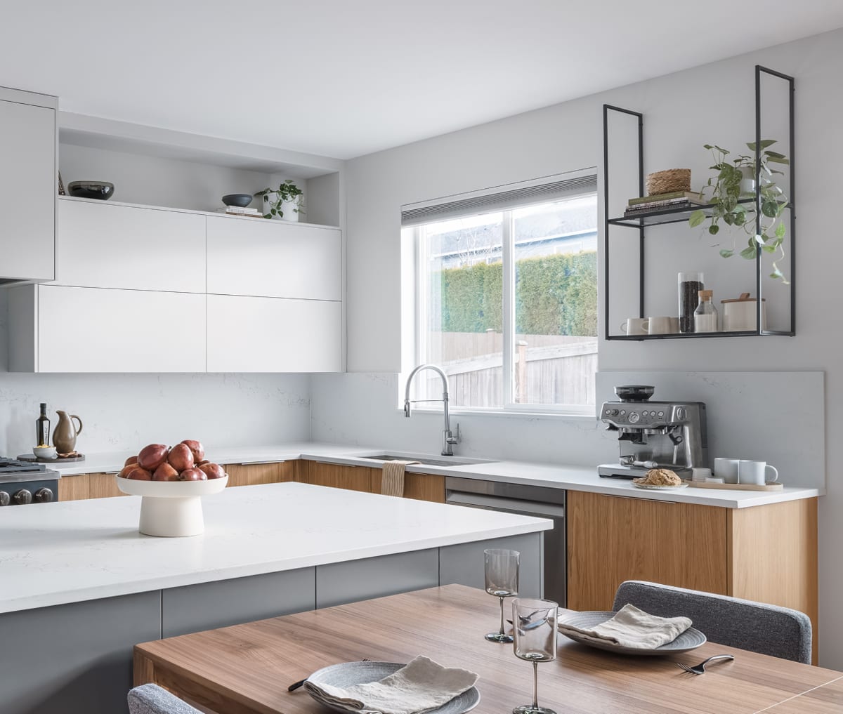 Wall-mounted black shelving with glass shelves above a kitchen coffee station