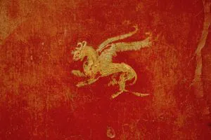 a gold on red painted griffin on Pompeii ruins