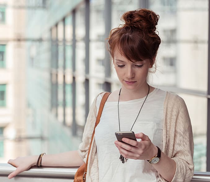 The image shows a woman checking notifications on her mobile phone.