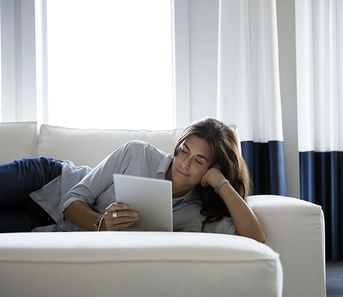 The image shows a couple on a sofa checking information on a tablet.