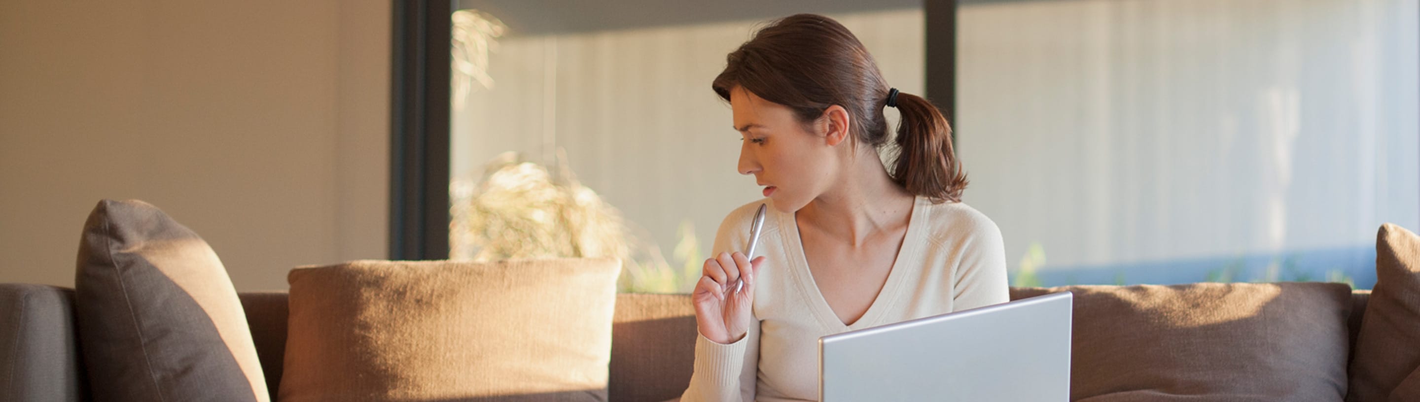 Woman on couch inquires via computer