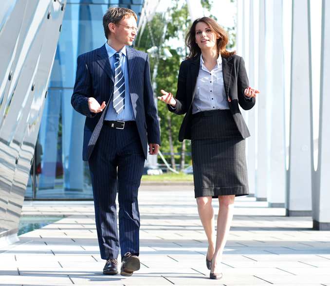 poslovnež in poslovna ženska hodita po hodniku. 