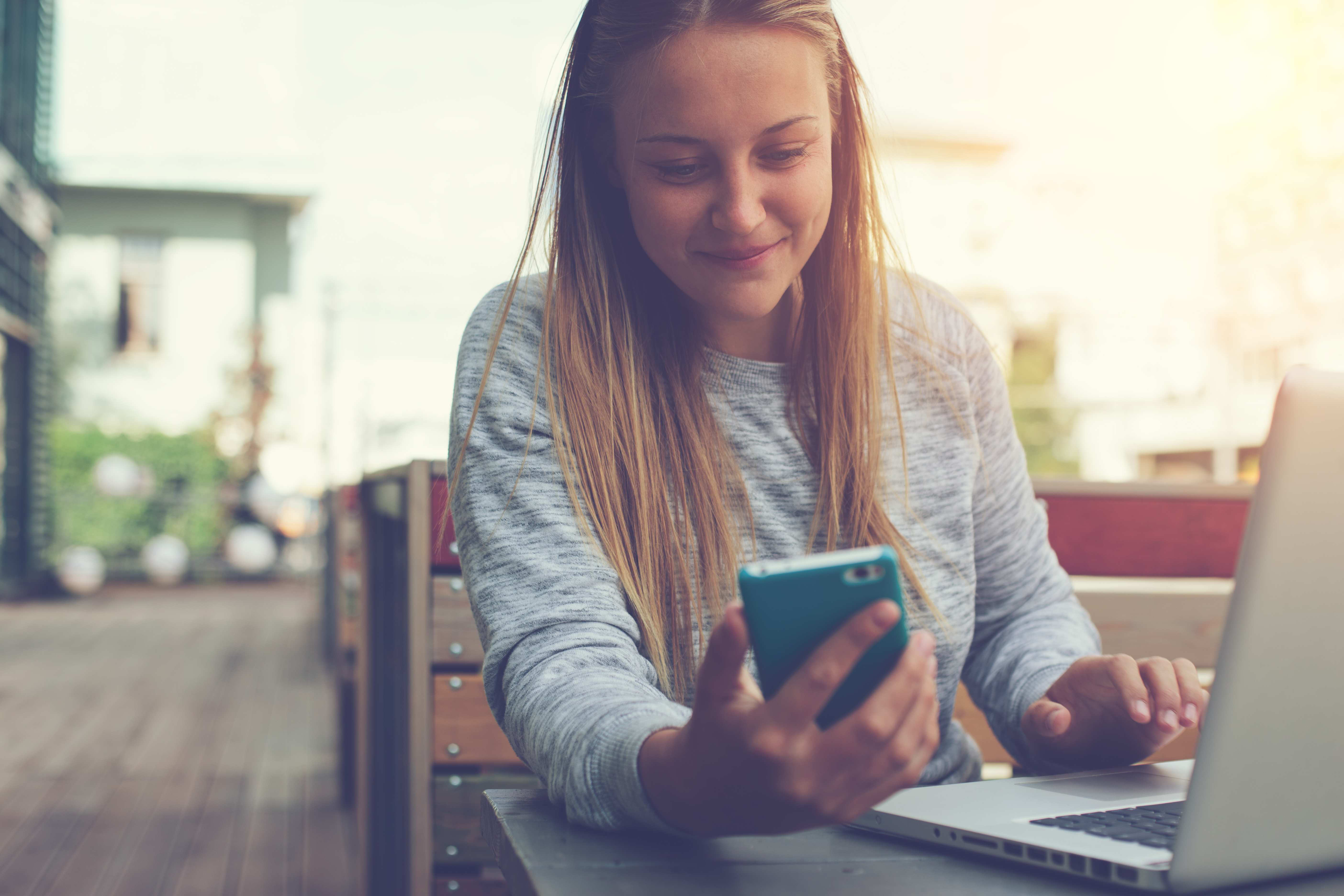 Girl with laptop and mobile phone in hands