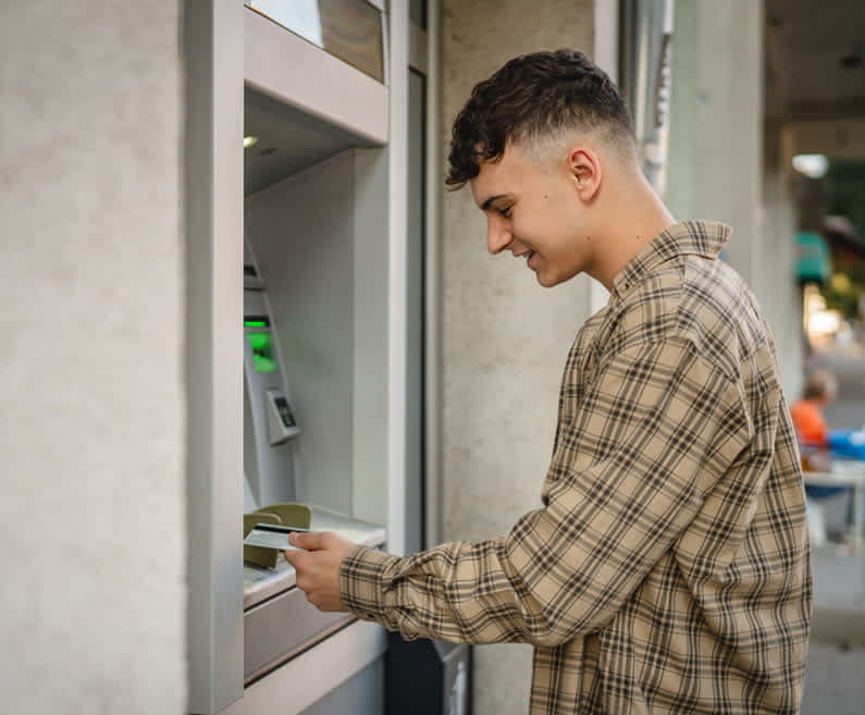 Slika prikazuje fanta pri uporabi bankomata.