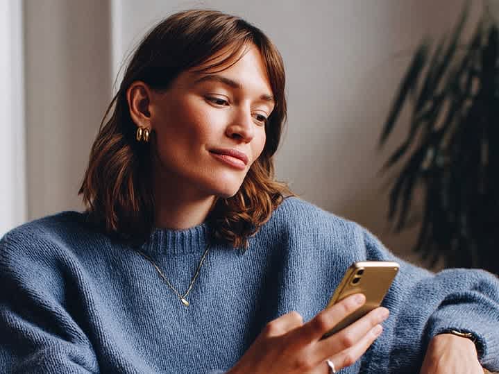 The image shows a woman checking notifications on her mobile phone.