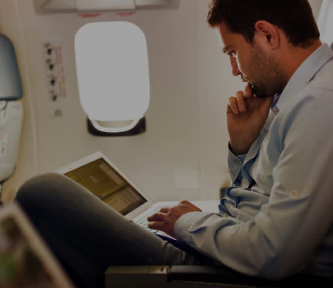 Moški na letalu s prenosnim računalnikom. 