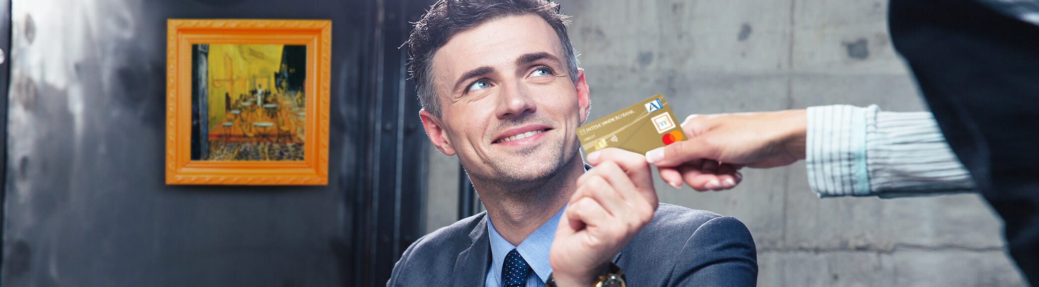 Na sliki je moški, ki plačuje z zlato kartico Mastercard z odloženim plačilom.