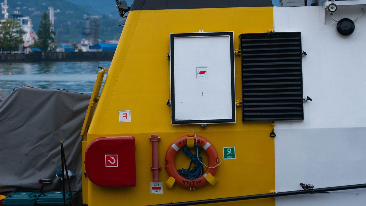 African ferry disasters may prompt safety revolution Detailed side view of a ship's deck featuring safety equipment and harbor background.