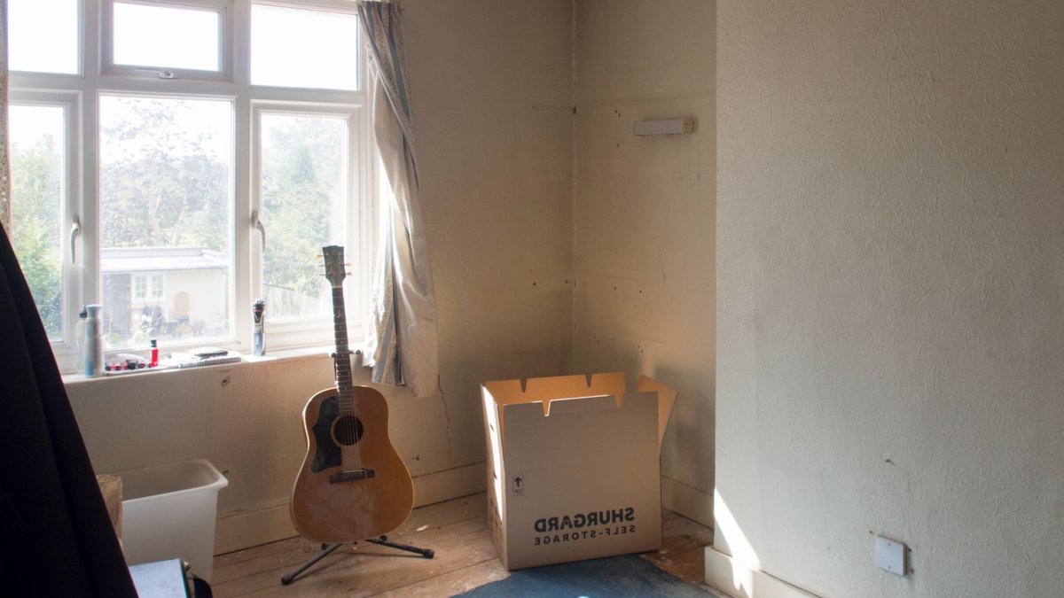 Architect's Tips for Seamless Side Return Extensions Sunlit room with guitar and moving box indicating home improvement work.