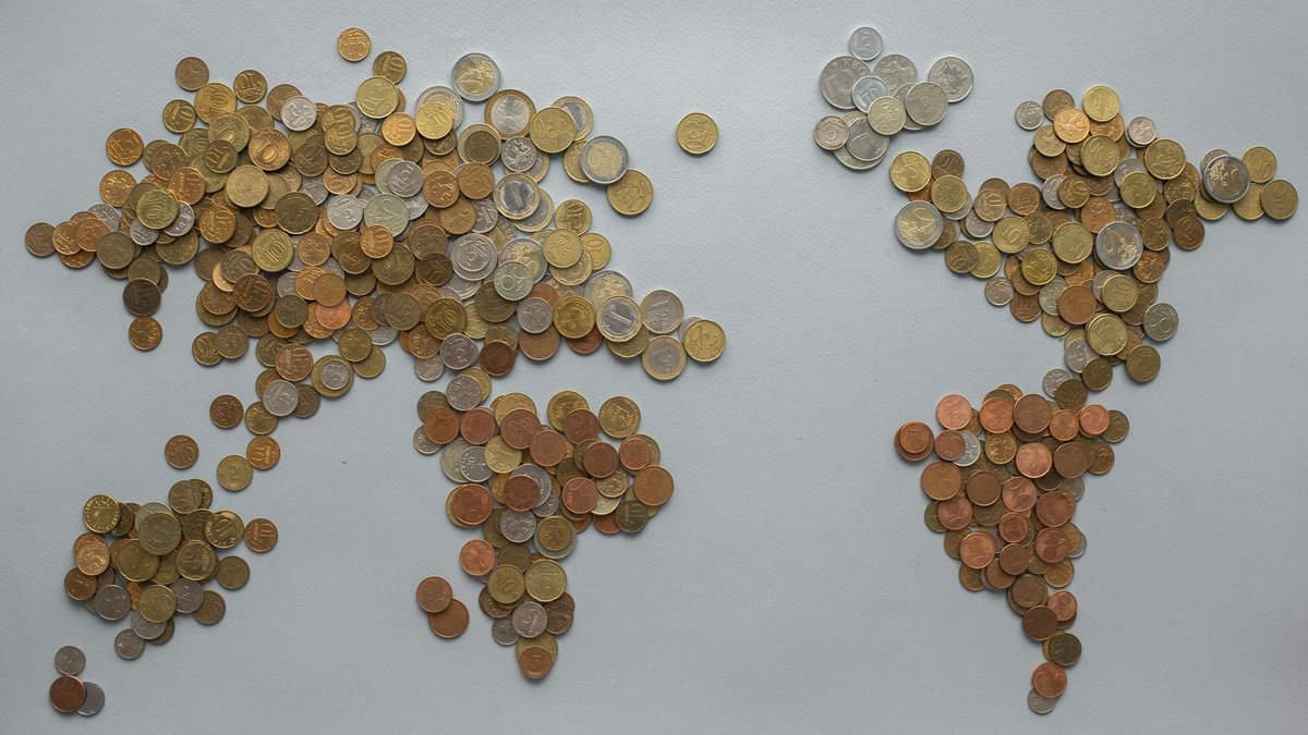 Creative world map made from assorted coins on a solid gray backdrop, symbolizing global finance.