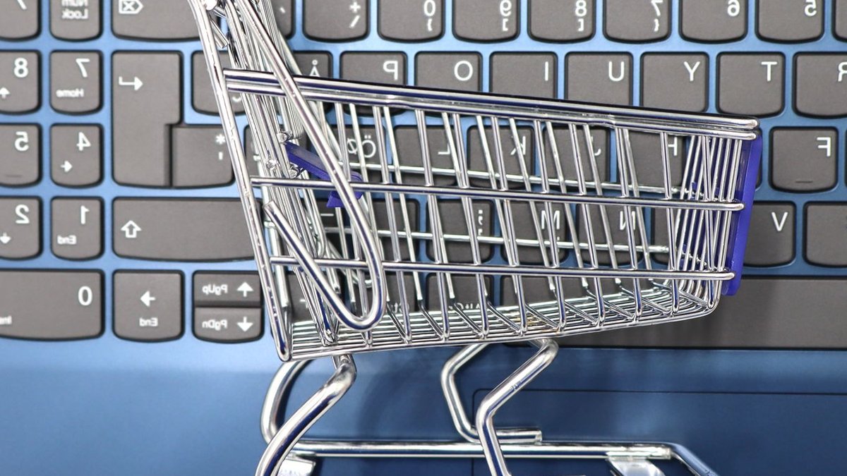 A miniature shopping cart placed on a laptop keyboard symbolizing online shopping and e-commerce.