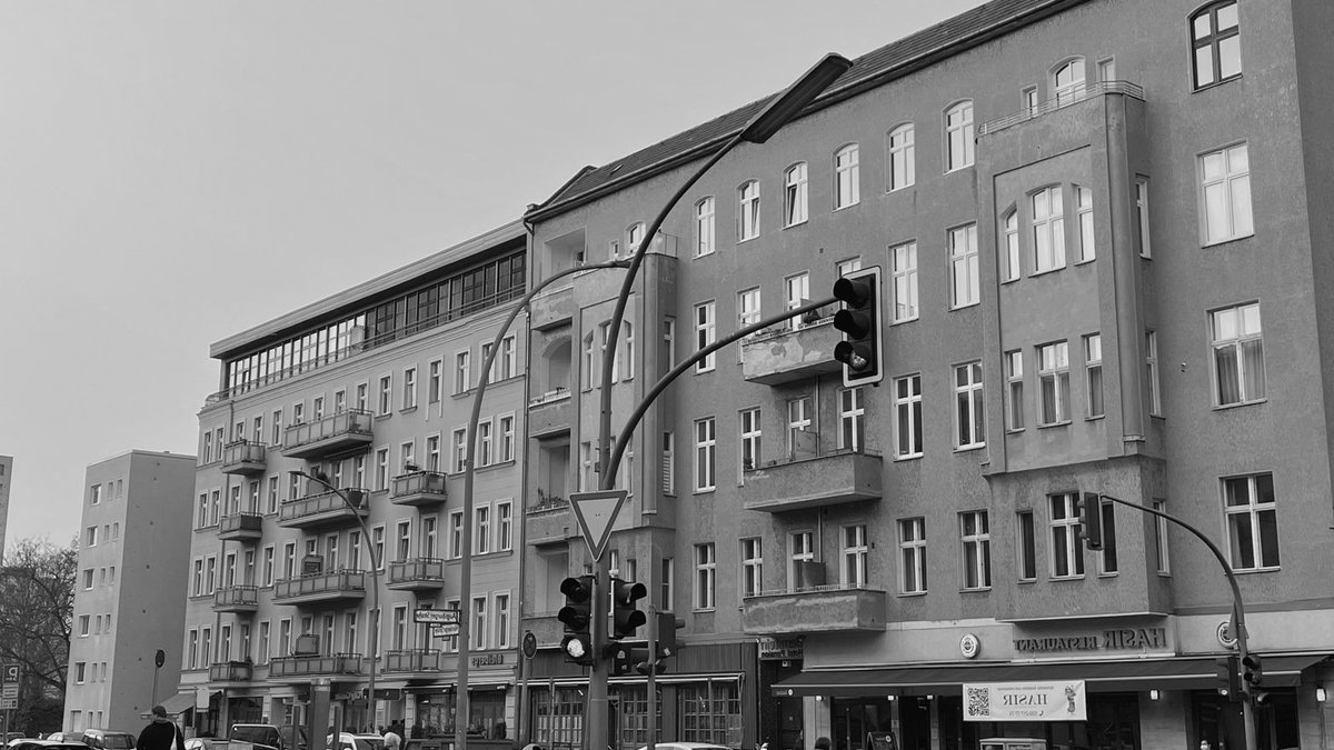 Black-and-white view of a busy street in Berlin with pedestrians and vehicles.