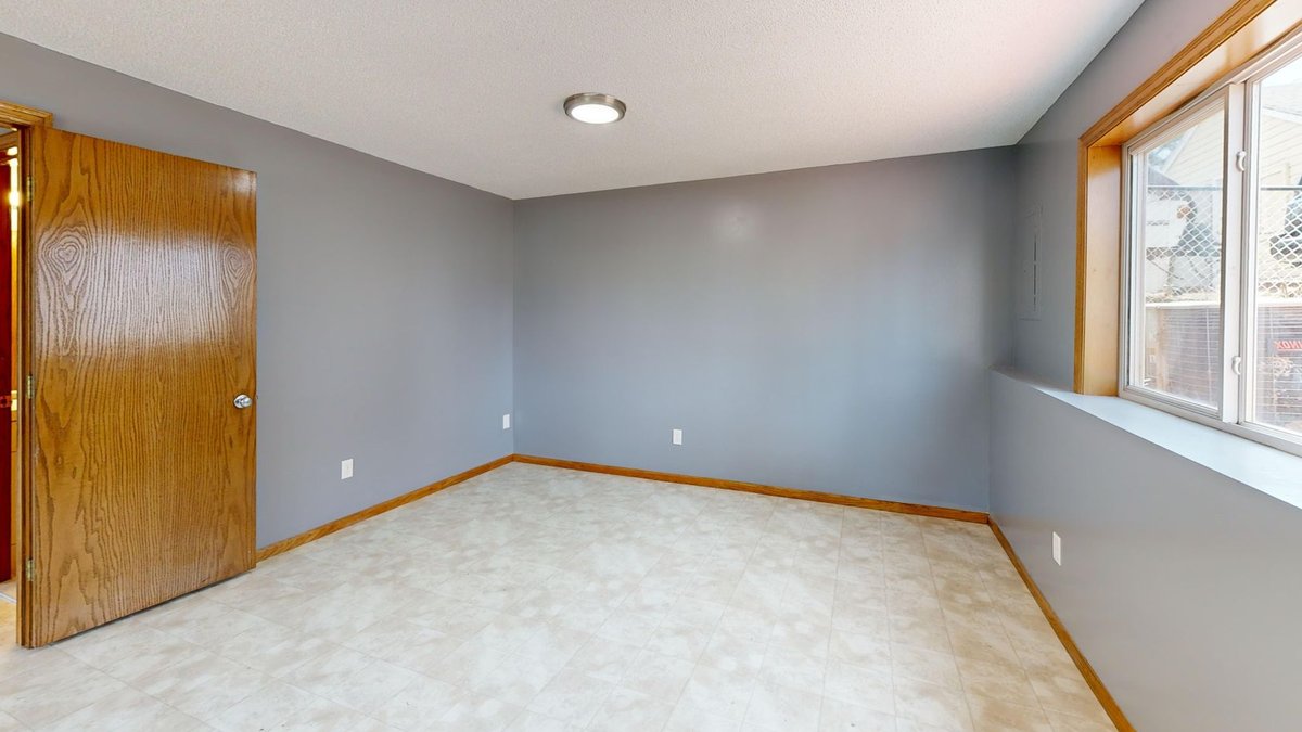 Home Renovation: Key Factors to Avoid Costly Mistakes Spacious empty room with natural light from window and wooden door.