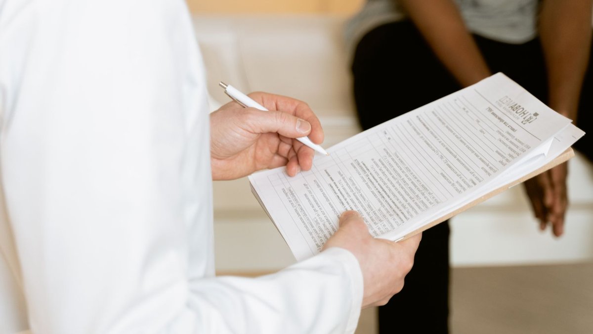 Healthcare professional reviews medical form during patient consultation in a clinic setting.