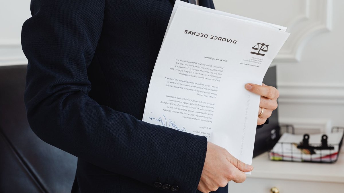 A person holding a divorce decree in an office setting, symbolizing legal proceedings.