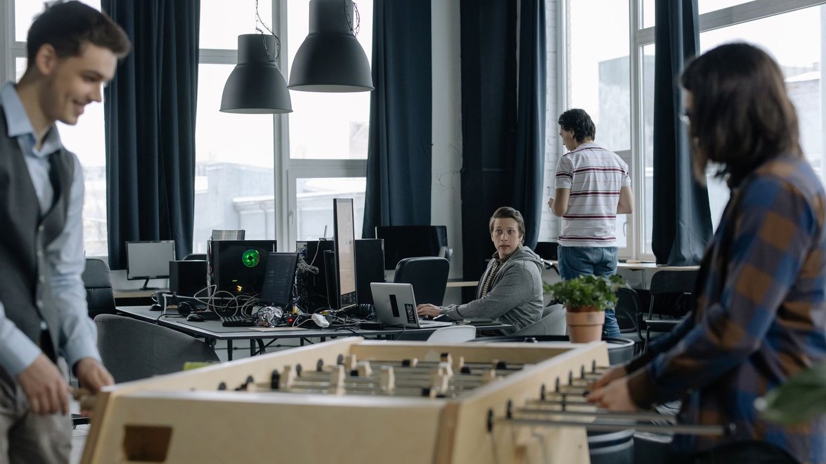 Indian firms shift to flexible data-driven benefits A modern office environment featuring a foosball table with employees engaging in teamwork.