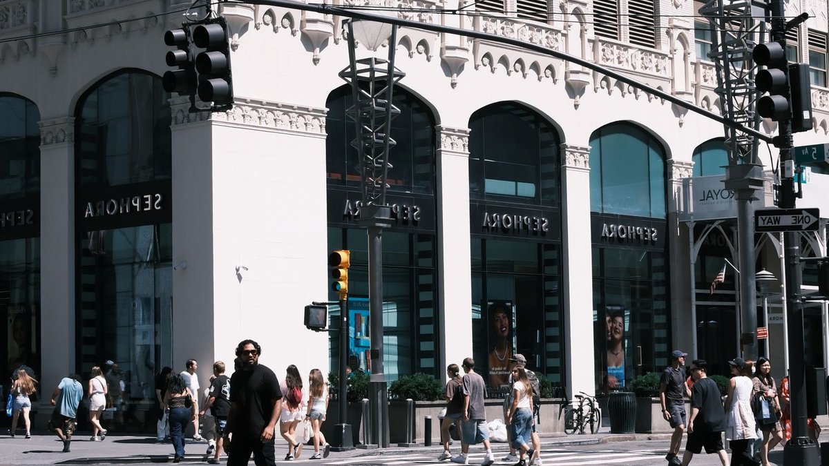 A lively city scene showcasing a Sephora storefront with pedestrians crossing the street.