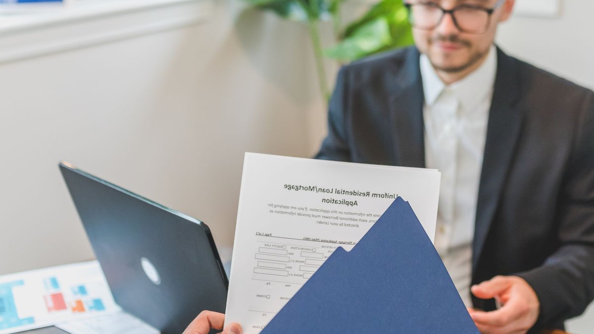 Mortgage broker and client discussing loan application with documents on table.