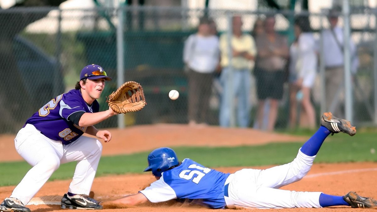 A thrilling moment in a baseball game as a runner slides into base while the fielder prepares to catch the ball.