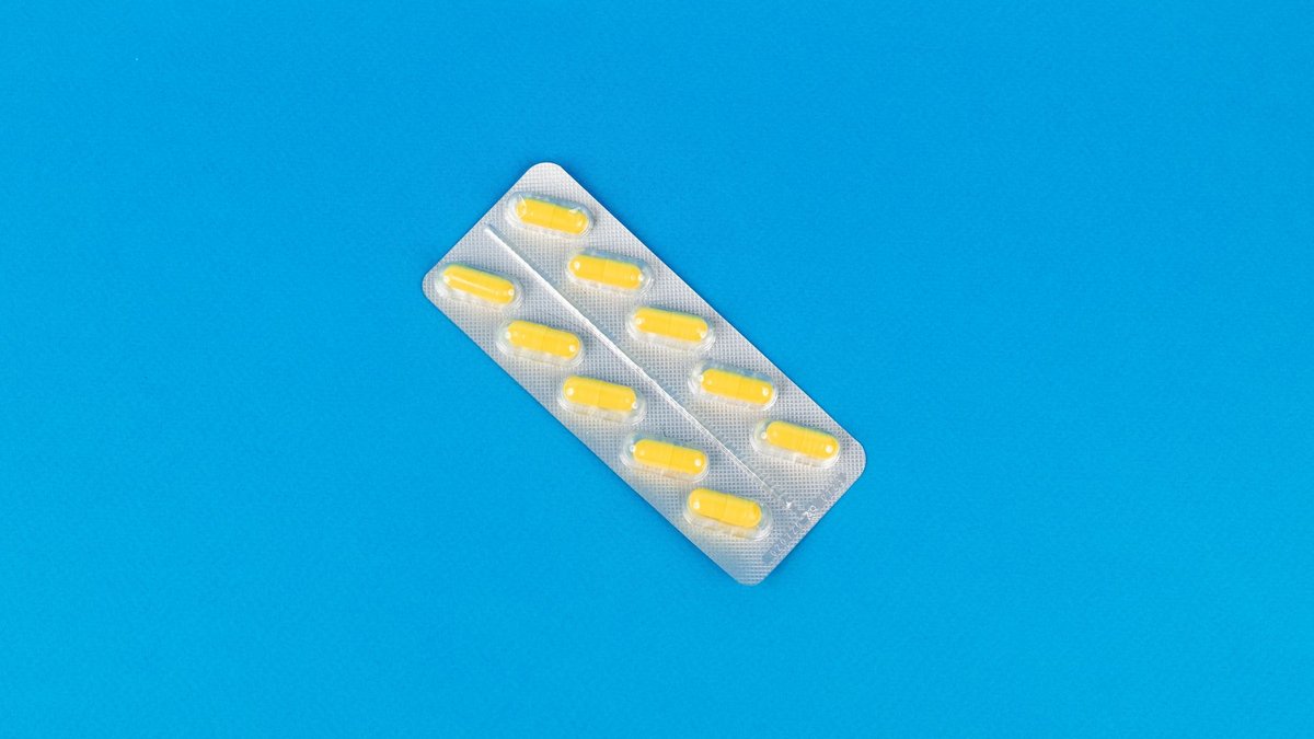 Pack of yellow capsules on a vibrant blue background symbolizing modern medicine.