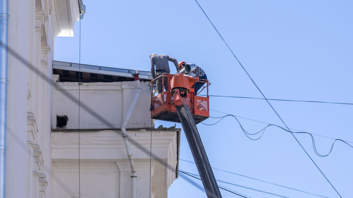 Rivers workers win appeal to enforce unpaid wages ruling Workers on lift repairing building façade under clear sky.