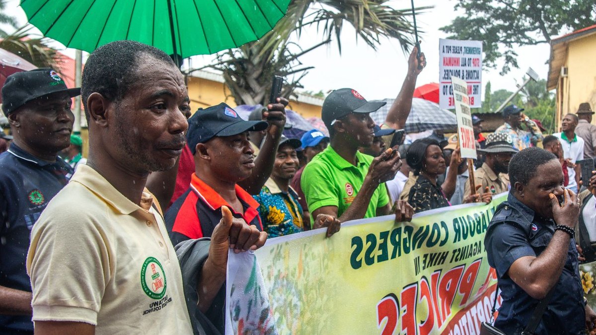 Nigerians give Tinubu mixed ratings in Lagos survey A diverse group of protesters with placards rally in the rain, advocating for economic change.