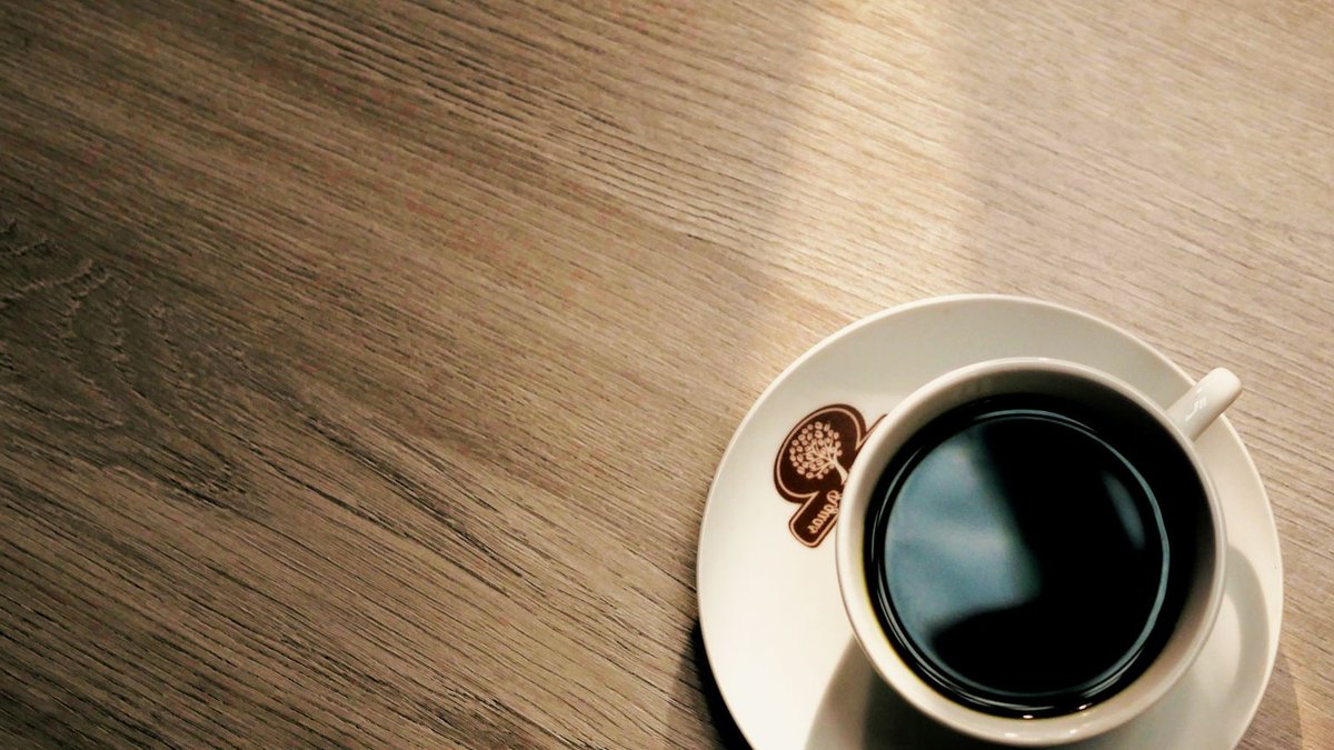 Designer reveals secrets for creating stylish coffee stations at home A warm cup of coffee sits subtly in a sunbeam on a wooden table. Perfect for serene morning vibes.