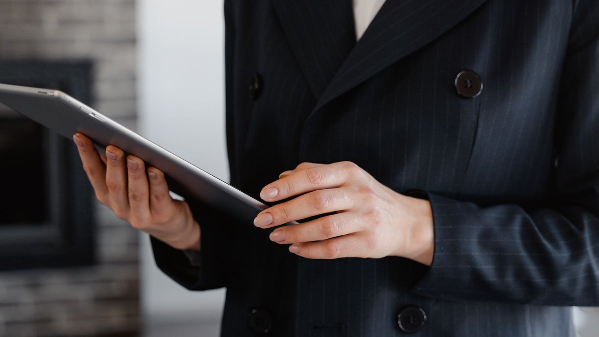 Close-up of a woman in a blazer using a digital tablet indoors.