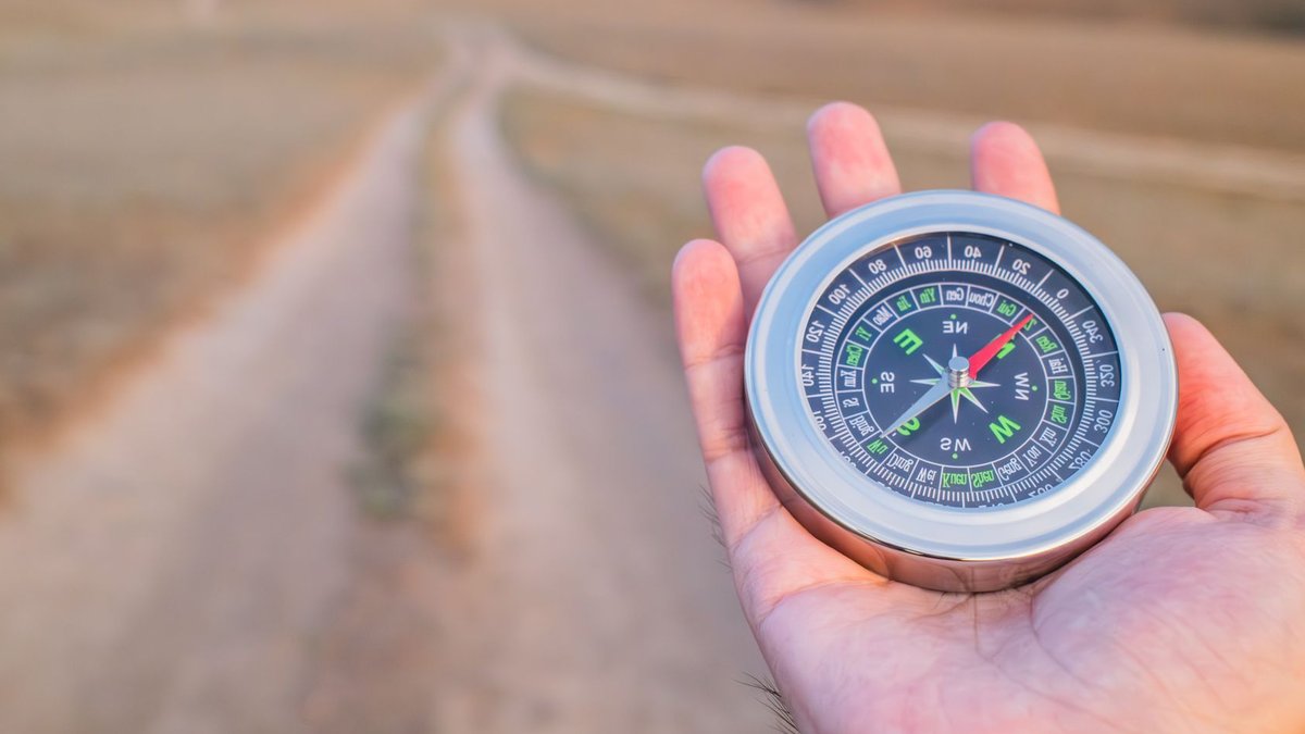 Hand holding a compass guiding along a dusty path outdoors. Perfect for travel and exploration themes.