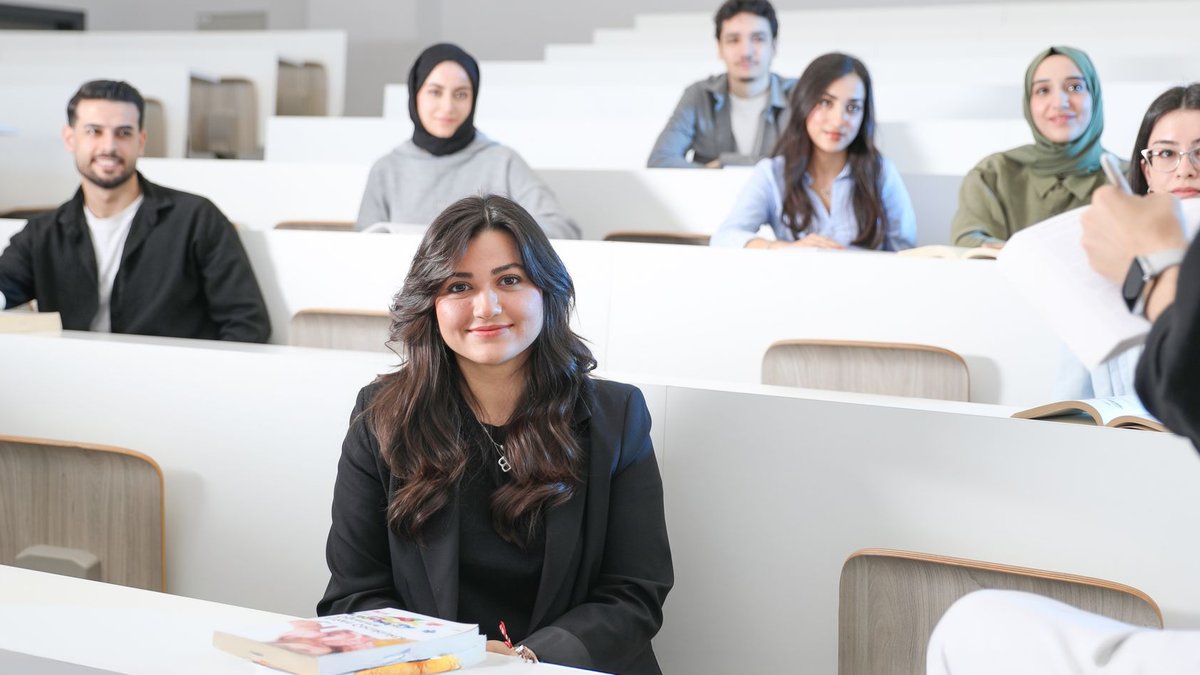 Students listening attentively in a bright university lecture hall.