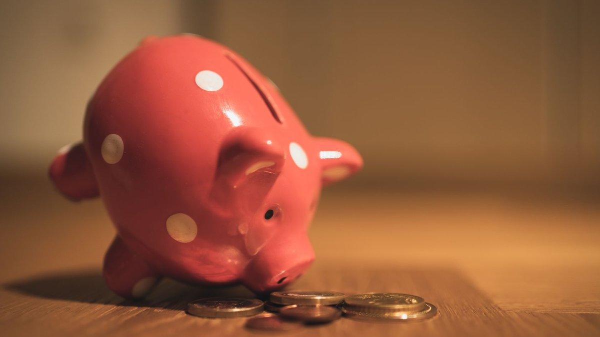 Private bank stocks surge ahead of RBI policy decision A red ceramic piggy bank with polka dots surrounded by coins, symbolizing savings and finance.