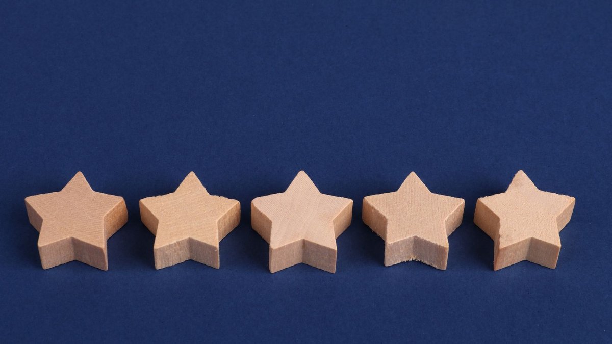 Five wooden stars on a blue background representing a rating system or evaluation concept.