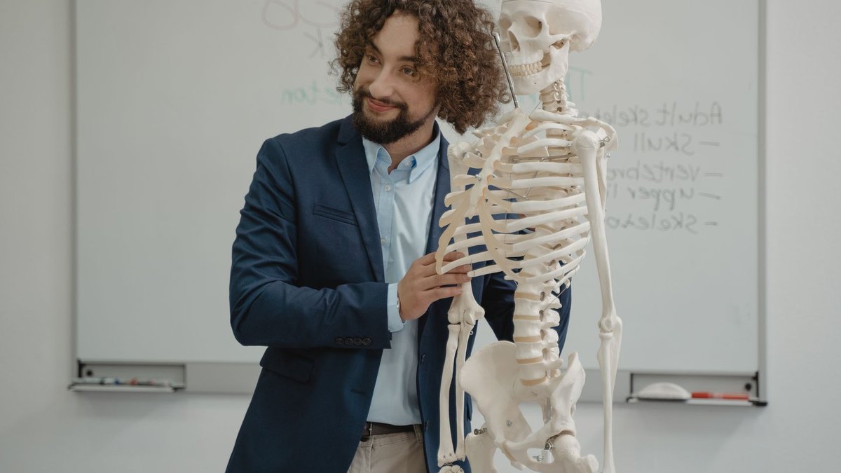 A biology teacher demonstrates the human skeleton model in an engaging classroom setting.