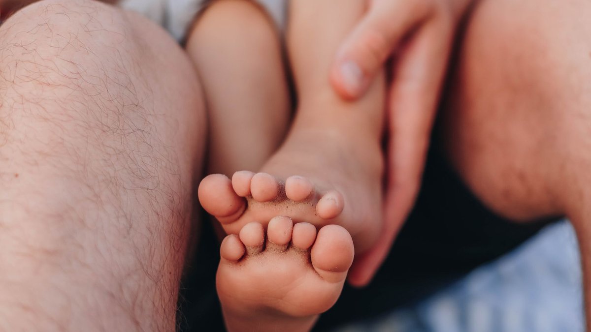 A tender close-up of baby feet being gently held by a parent, evoking warmth and care.