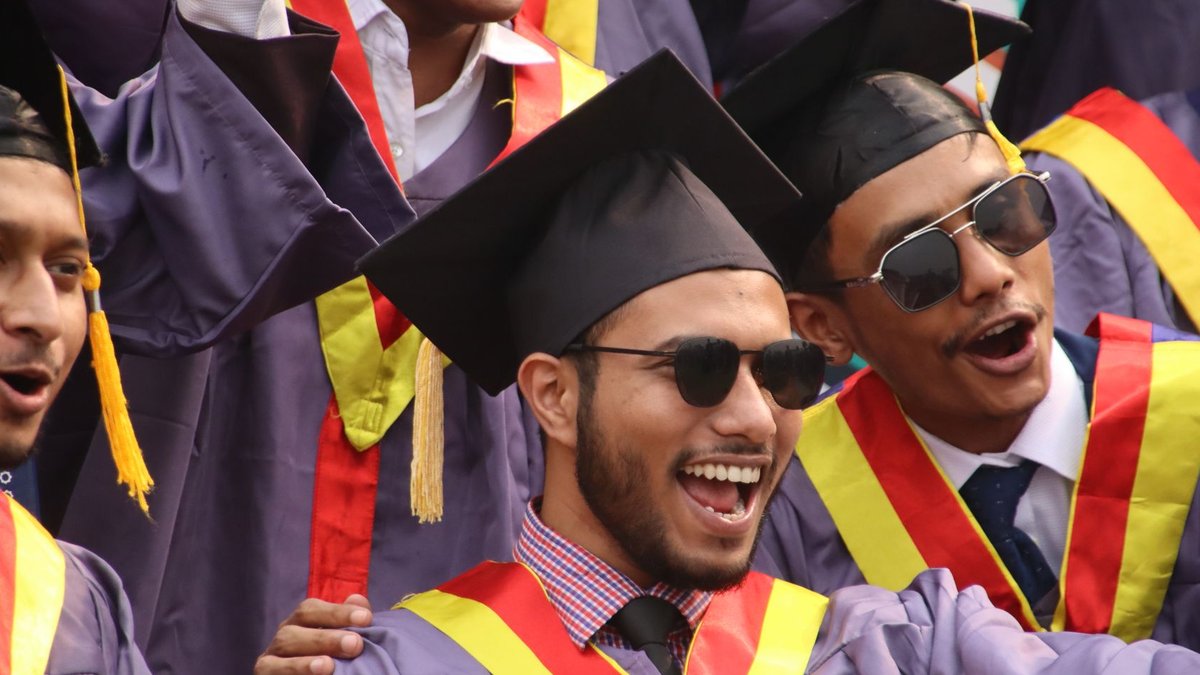 Group of diverse graduates celebrating with enthusiasm in convocation attire.