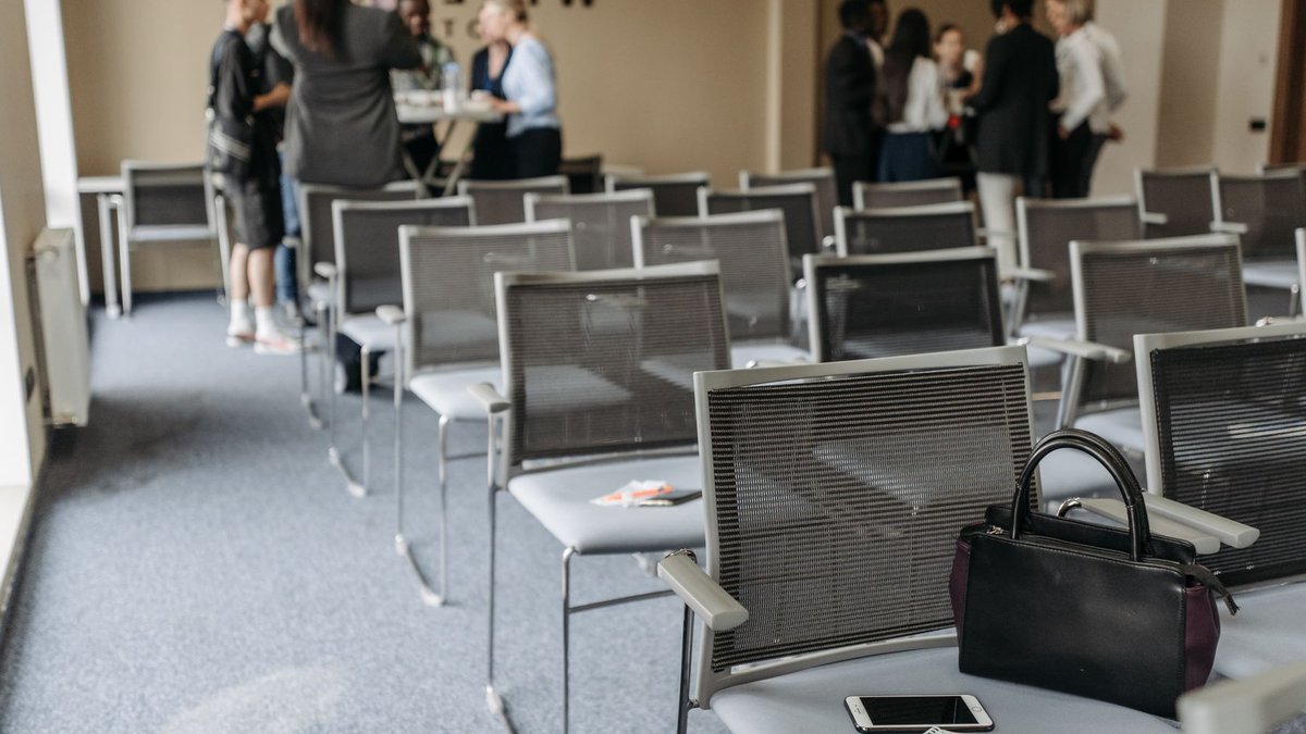 An empty conference room with chairs and a group of people gathered at the back.