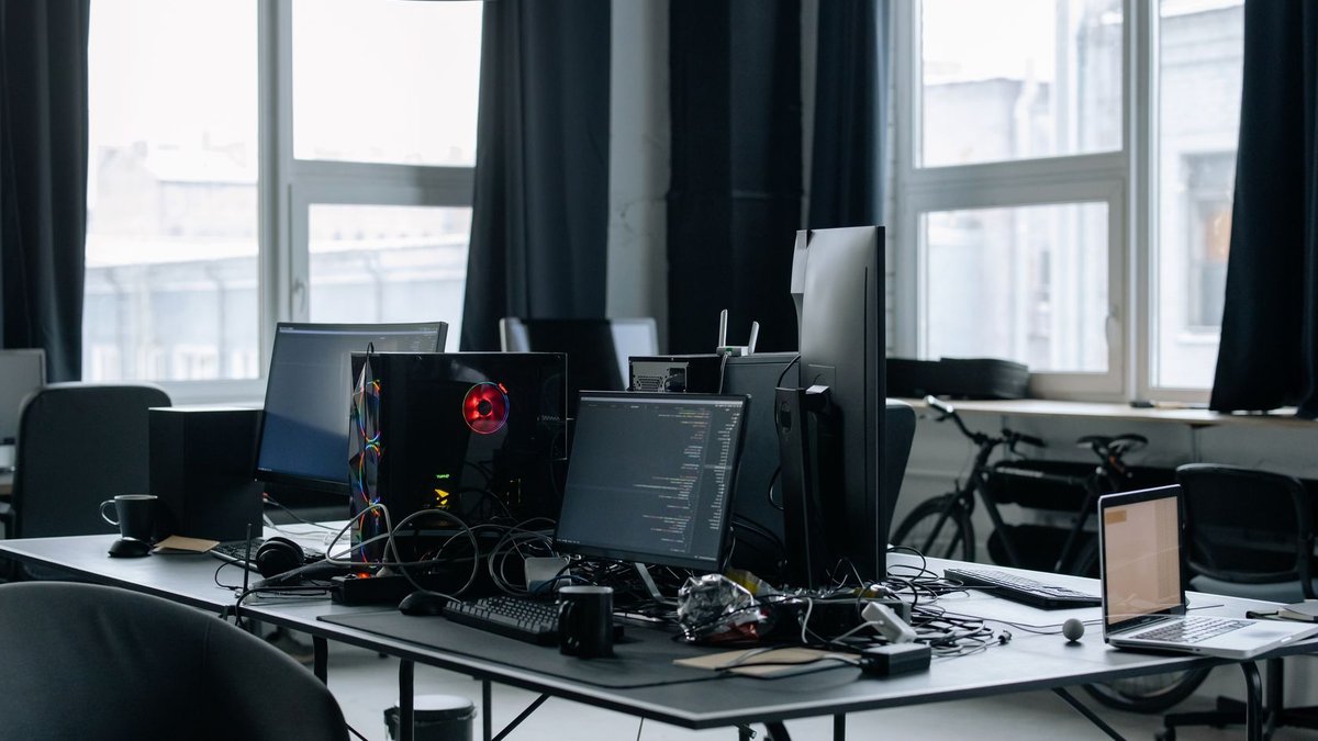 Contemporary workspace featuring computers, coding screens, and office essentials in a tech environment.