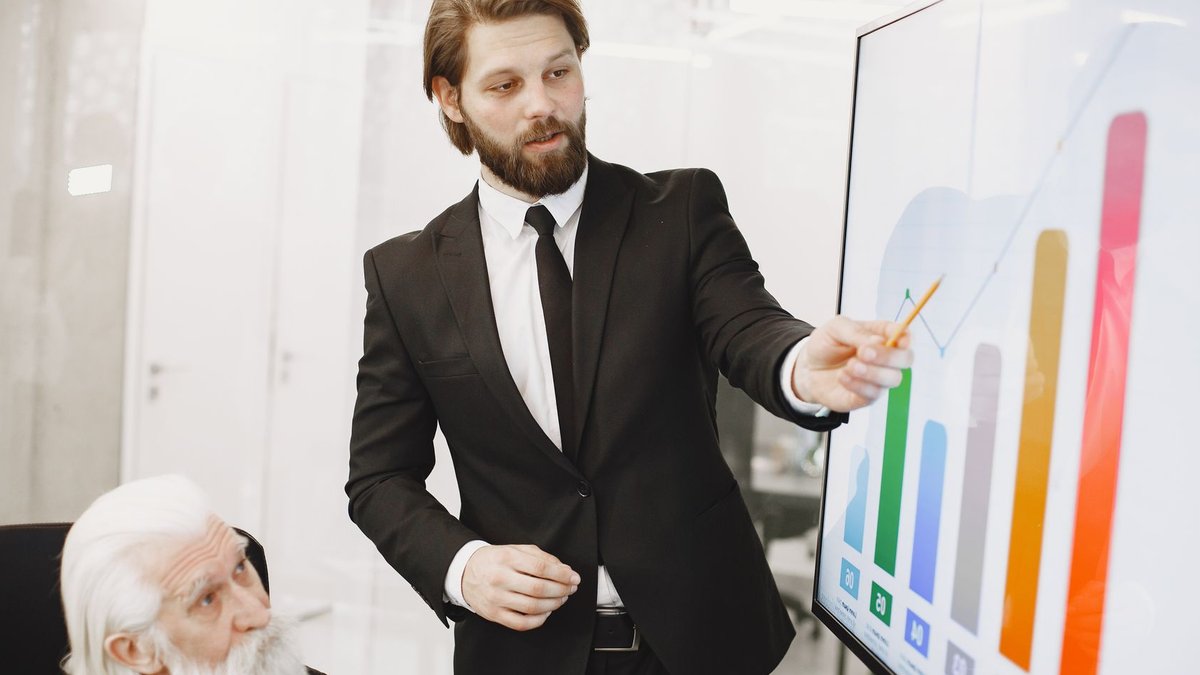 Two businessmen discussing data trends during a presentation in a modern office setting.