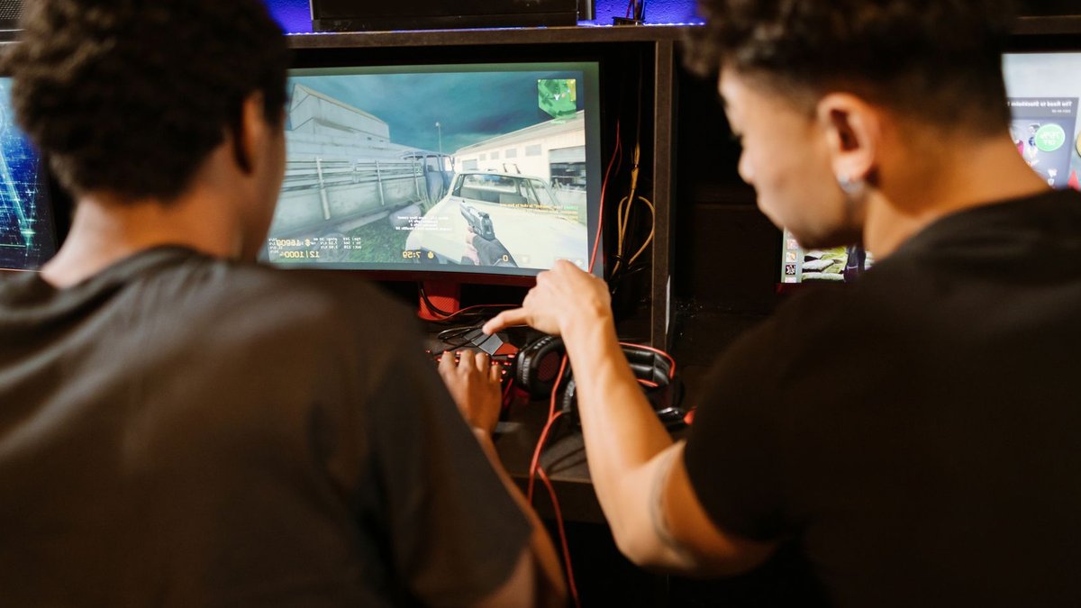 Rainbow Six Siege Offline After Massive Credit Exploit Two young men playing a multiplayer computer game at an arcade with enthusiasm and focus.